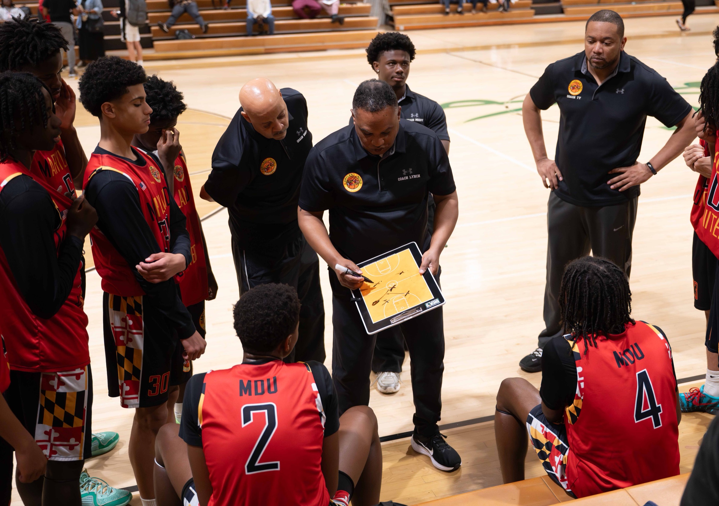 Maryland United players and coaches gathered around a clipboard during a timeout